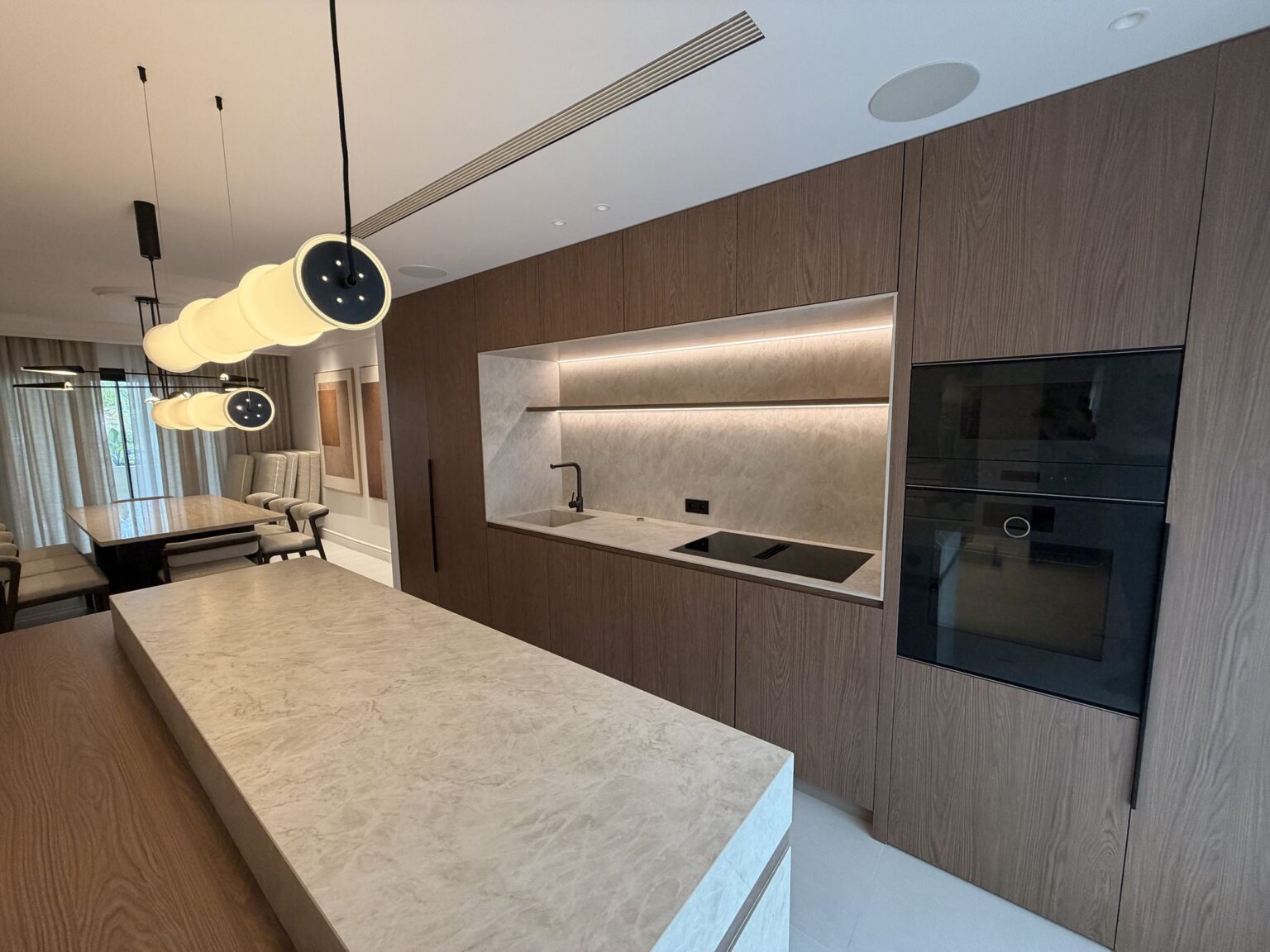 Cocina con isla de piedra y mobiliario de madera en la reforma integral