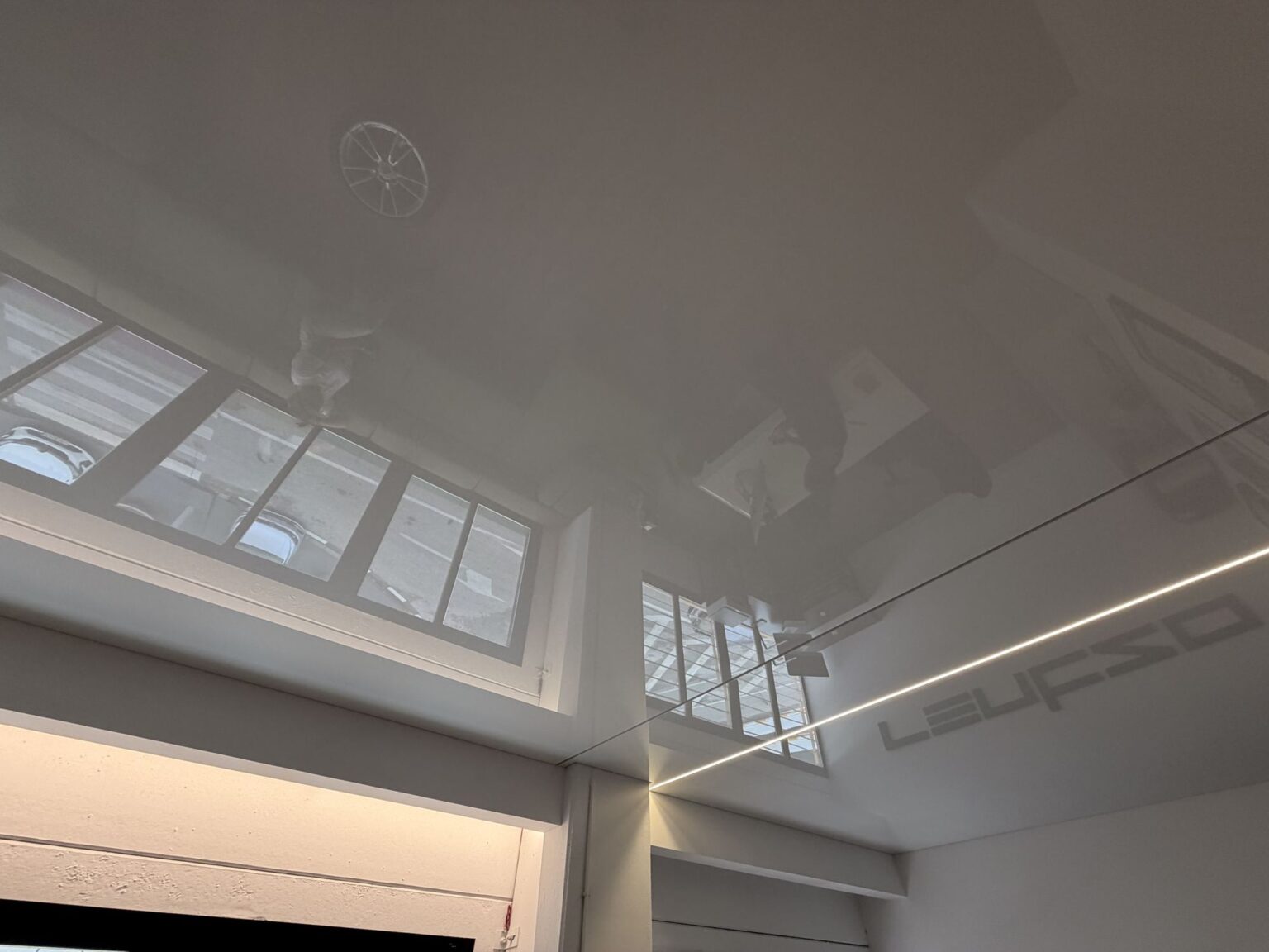 Techo tensado lacado blanco que refleja las ventanas de la oficina