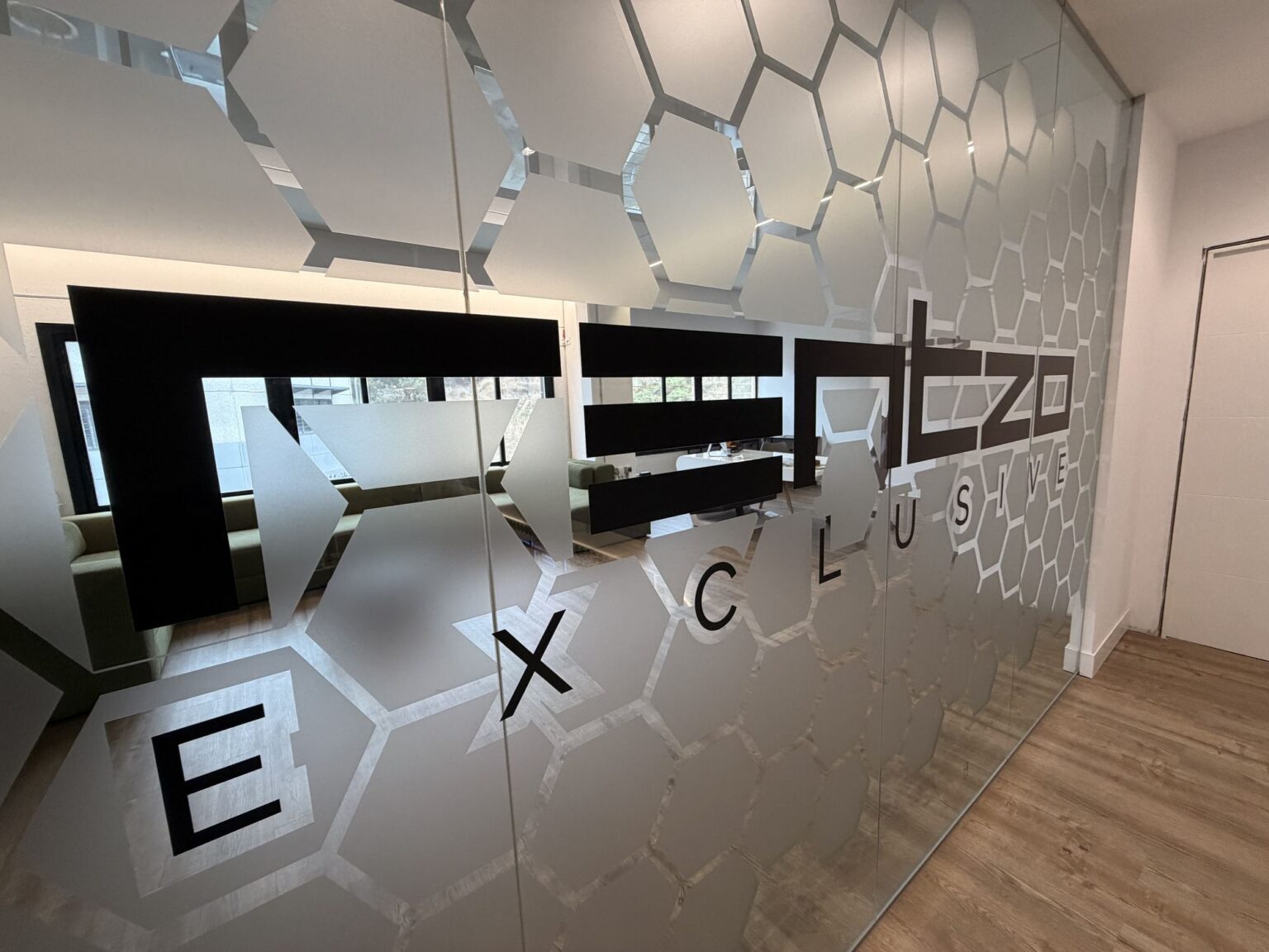 Cristal con vinilo hexagonal y logotipo Rentzo Exclusive en la oficina