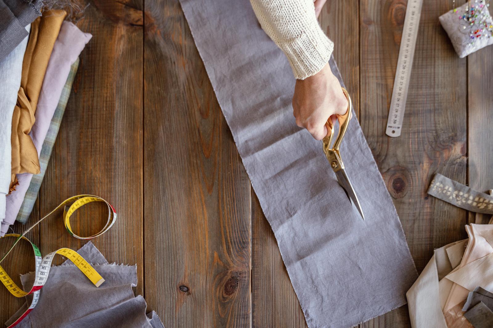 Manos cortando tela sobre una mesa de madera